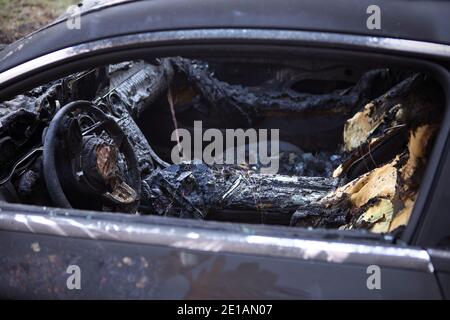 Primo piano dell'auto bruciata. Volante e cruscotto. Auto dopo il fuoco. Arson auto. Incidente sulla strada a causa della velocità. Esplosione. Foto Stock