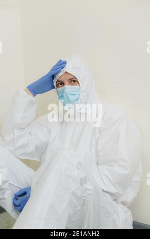 Un medico triste si siede sul pavimento nel corridoio dell'ospedale. Operatori sanitari durante la pandemia di Coronavirus Covid19 Foto Stock