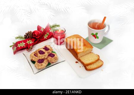 Torta fatta in casa e biscotti appena sfornati con arco rosso, candela e sidro caldo su sfondo bianco. Tema di Natale. Foto Stock