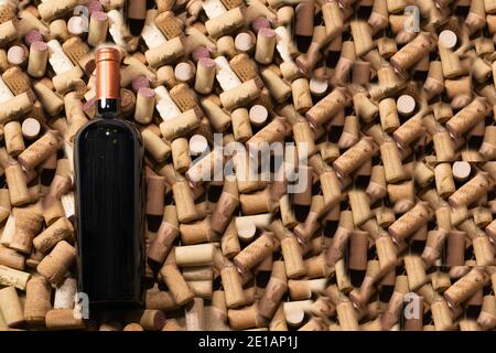 Bottiglia di vino rosso in posizione orizzontale su un lotto di tappi Foto Stock