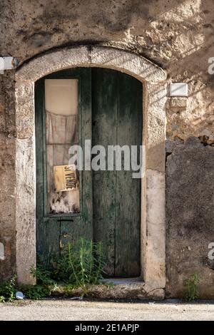 Vecchia porta in legno di una casa abbandonata con un cartello 'in vendita', Italia Foto Stock