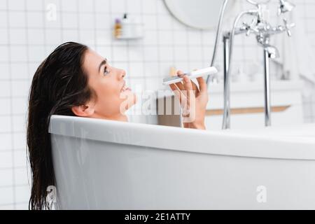 donna allegra che parla sul telefono cellulare mentre si fa il bagno Foto Stock