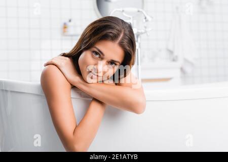 felice giovane donna che sorride alla macchina fotografica mentre prende il bagno a. casa Foto Stock