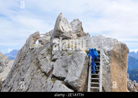 Salita in montagna esposta: Donna su scala in ferrata nelle Alpi italiane Foto Stock