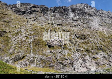 Cascate multiple su una scogliera sulla strada per Milford Sound, South Island, Nuova Zelanda Foto Stock