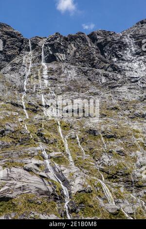 Cascate multiple su una scogliera sulla strada per Milford Sound, South Island, Nuova Zelanda Foto Stock