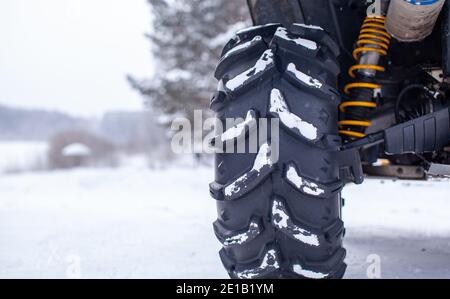 Primo piano di una ruota quadrupla e di una trazione integrale. ATV nella foresta in inverno. A cavallo di una quad. Foto Stock