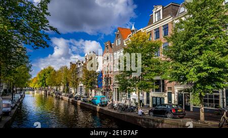 Case storiche, auto parcheggiate e biciclette lungo un canale nel centro storico di Amsterdam, Paesi Bassi Foto Stock