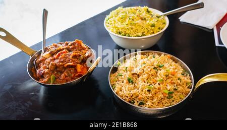 Fuoco selettivo di riso fritto vegetale, funghi Kadai e piselli Pulao servito su un tavolo nero. Foto Stock