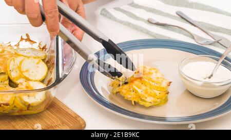 Ricetta di zucchine al forno. Fettine di zucchine con sale di condimento, pepe nero e formaggio, servite con panna acida. Basso-carburatori facile cheesy zucchine cuocere reci Foto Stock