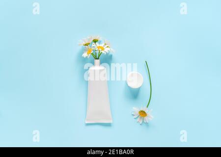 Bouquet di fiori di camomilla da cosmetici, tubo medico bianco per crema, unguento, dentifricio o altro prodotto. Concetto naturale cosmo organico erboristico Foto Stock