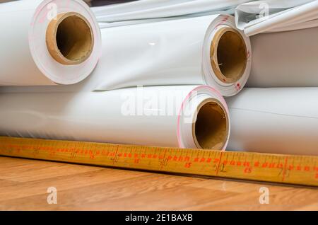 Rotoli bianchi di pellicola di PVC sono sul tavolo in officina per la produzione di soffitti estensibili. Produzione di soffitti allungati. Foto Stock