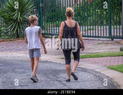 Johannesburg, Sudafrica - una madre e un figlio non identificati camminano lungo la strada con maschere durante la pandemia del covid-19 Foto Stock