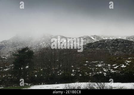 Paesaggio montano con capes nevosi in una giornata piovosa, come la luce entra attraverso le nuvole Foto Stock