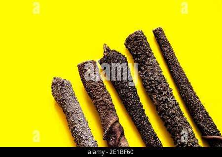 Concetto naturale di dolcetti essiccati per animali domestici. Bastoni di stomaco di vacca secca su sfondo giallo. Vista dall'alto, primo piano. Foto Stock