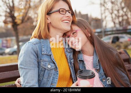 Madre e figlia felici ridendo e abbracciando all'aperto su un caldo giorno d'autunno Foto Stock