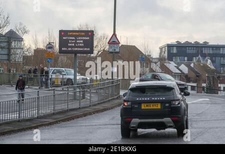 Le automobili passano un segnale di informazione che informa la gente circa il blocco nazionale a Staines-upon-Thames in Surrey. Il primo ministro Boris Johnson ha ordinato un nuovo blocco nazionale per l'Inghilterra, il che significa che le persone potranno lasciare le proprie case solo per motivi limitati, con misure che dovrebbero rimanere in vigore fino a metà febbraio. Foto Stock