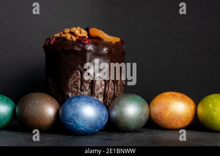 Torta di Pasqua e uova colorate su sfondo nero. Cibo per le vacanze e concetto di pasqua Foto Stock