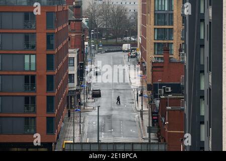 Un uomo cammina lungo una vicina strada deserta Bromsgrove nel centro di Birmingham durante nuove misure di blocco nazionale. Il primo ministro Boris Johnson ha ordinato un nuovo blocco nazionale per l'Inghilterra, il che significa che le persone potranno lasciare le proprie case solo per motivi limitati, con misure che dovrebbero rimanere in vigore fino a metà febbraio. Foto Stock