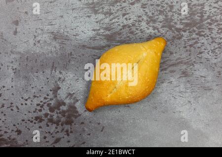 Vista dall'alto di un rotolo di pane di bolillo appena sfornato su uno sfondo grigio dalle macchie. Foto Stock