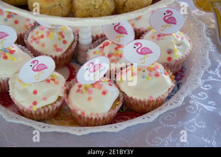 Primo piano di cupcake fatti in casa con decorazione rosa dei bastoni di fenicottero su un piatto, concetto di festa, dolci per la celebrazione di compleanno, fuoco selettivo Foto Stock