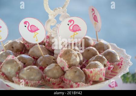 Primo piano di piccoli dessert fatti in casa con decorazione rosa dei bastoni di fenicottero su un piatto, concetto di festa, dolci per la celebrazione di compleanno, fuoco selettivo Foto Stock