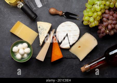 Formaggi vari, uva e vino bianco. Vista dall'alto in piano Foto Stock