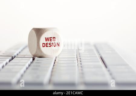 La parola web design con icona freccia su cubo di legno con tastiera per computer. Business, tecnologia e Internet Concept. Foto Stock