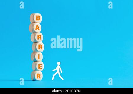 La parola barriera su cubi di legno a più livelli con un bastone uomo a piedi su sfondo blu. Superare stress, pressioni o difficoltà nel concetto di business. Foto Stock
