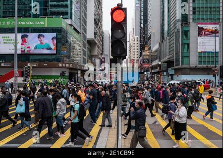 Le persone che indossano maschere per il viso come misura preventiva contro la diffusione del Coronavirus Covid-19 attraversano la strada ad un incrocio zebra a Hong Kong. Foto Stock