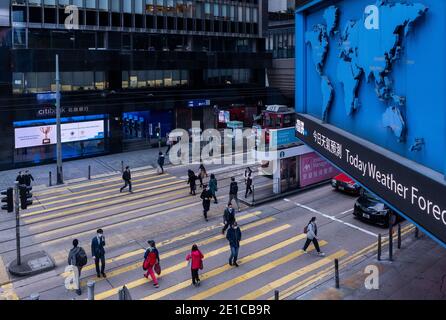 Le persone che indossano maschere per il viso come misura preventiva contro la diffusione del Coronavirus Covid-19 attraversano la strada ad un incrocio zebra a Hong Kong. Foto Stock