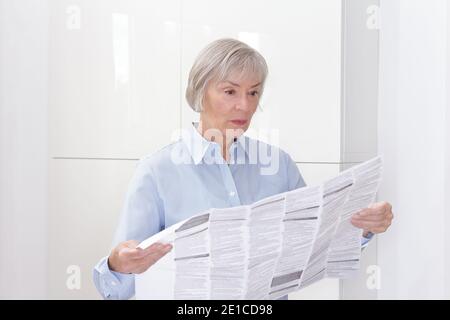 Donna anziana con un enorme foglio informativo per il paziente per la sua medicina prescritta, spazio di copia. Foto Stock