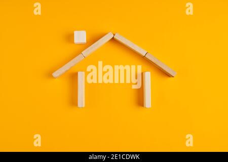 Casa fatta di blocchi di legno su sfondo giallo. Proprietà domestica e concetto di assicurazione. Foto Stock