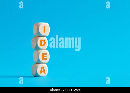 La parola idea su cubi di legno a più livelli su sfondo blu. Concetto di costruzione di idea. Foto Stock