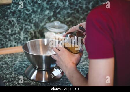 cuoci pesa lo zucchero su una bilancia elettronica per determinare il peso esatto. Aggiungere un sapore dolce all'impasto di pan di zenzero. Cottura dei biscotti natalizi. Foto Stock