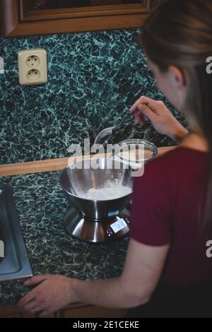 cuoci pesa lo zucchero su una bilancia elettronica per determinare il peso esatto. Aggiungere un sapore dolce all'impasto di pan di zenzero. Cottura dei biscotti natalizi. Foto Stock