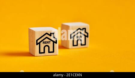 Icone della casa su cubetti di legno con opzioni di acquisto o affitto. Decisione di affittare un concetto di bene immobile. Foto Stock