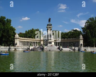 Gite in barca sul lago di El Estanque nel Parque del Retiro (Parco del Retiro) a Madrid. Sullo sfondo, un colonnato circonda il monumento al Re Alfonso XII Foto Stock