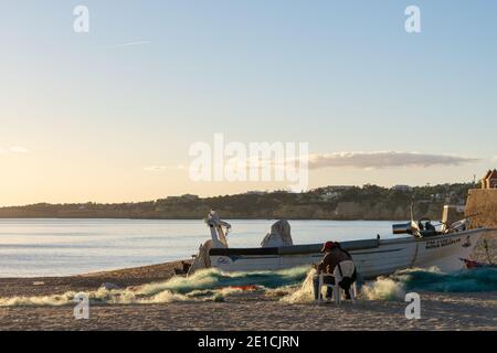 Amarcao da Pera, Portogallo - 30 dicembre 2020: Pescatori della Praia dos Pescadores che minacciano e riparano i loro attrezzi e reti Foto Stock