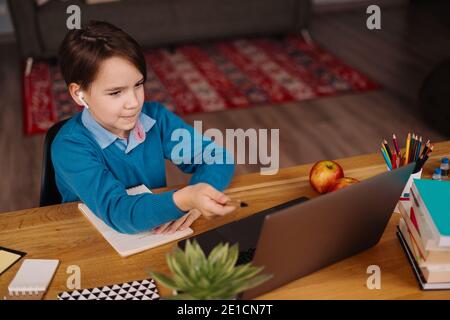 Un ragazzo di Preteen usa un laptop per fare le classi in linea. E-Education formazione a distanza, formazione a casa. Foto Stock