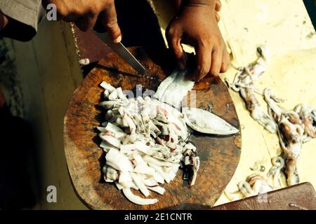 Il pescatore taglia l'esca-calamaro di pesca nel Golfo della Thailandia. Foto Stock