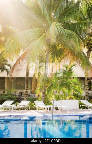 La piscina dell'hotel è vicina e il sole splende tra le palme di Cozumel, Messico Foto Stock