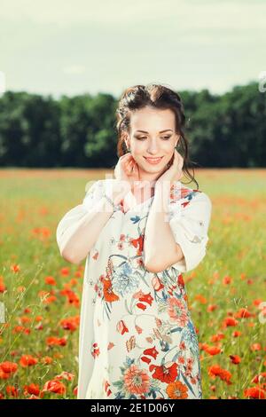 Una bella ragazza in un campo di papaveri rossi in fiore. Foto Stock