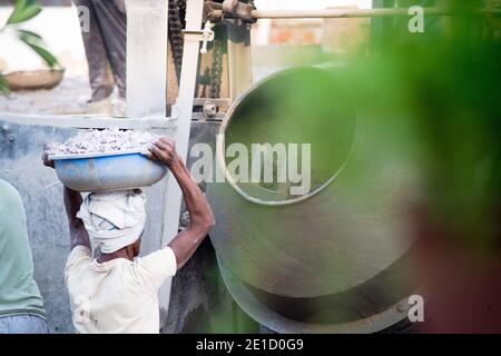 zoomed in colpo di operai di costruzione underprived indiani che trasportano la sabbia, il cemento, le pietre e l'acqua sulla loro testa per caricare in un miscelatore per fare Foto Stock