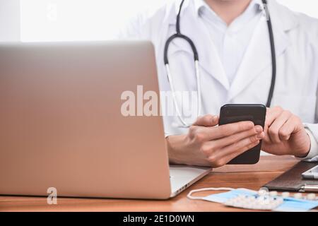 Medico che utilizza un telefono cellulare al lavoro Foto Stock