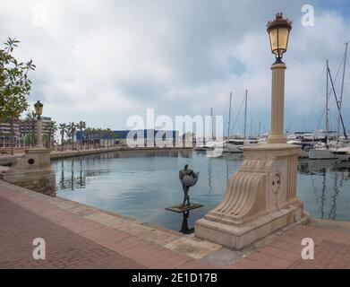 Vista del porto di Alicante con barche a vela ormeggiate e la statua di Icarus che tiene ali.Costa Blanca, Spagna. Foto Stock