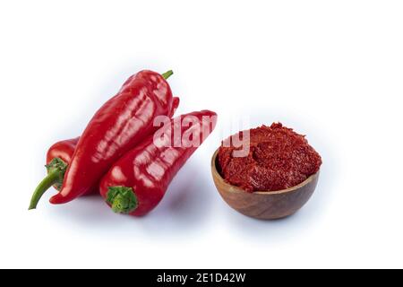 Pasta di pepe di stile turco (biber salcasi). Ciotola di legno con salsa rossa e peperoncino fresco isolato su bianco. Foto Stock