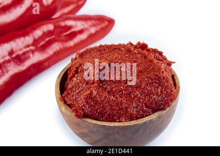 Pasta di pepe di stile turco (biber salcasi). Ciotola di legno con salsa rossa e peperoncino fresco isolato su bianco. Foto Stock