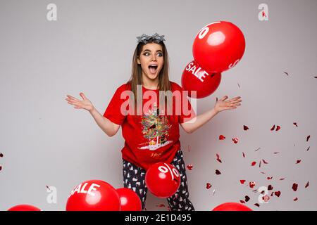 Sorpresa bella donna con molti palloncini rossi in studio Foto Stock
