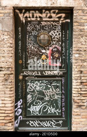 Antica porta in legno coperta di graffiti nel quartiere di Trastevere. Roma, Italia. Foto Stock